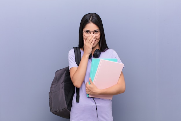 Mujer joven estudiante bastante latino contra la pared gris