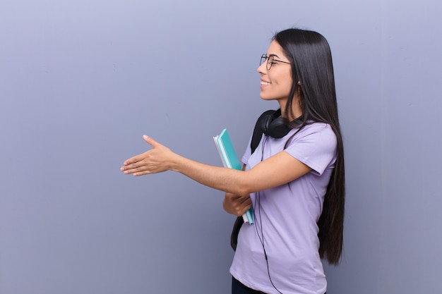 Mujer joven estudiante bastante latino contra la pared gris