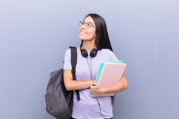 Mujer joven estudiante bastante latino contra la pared gris