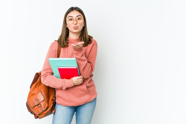 Mujer joven estudiante caucásica aislada sobre fondo blanco doblando los labios y sosteniendo las palmas para enviar beso de aire.