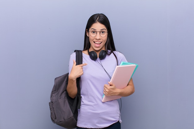 mujer joven estudiante contra la pared gris