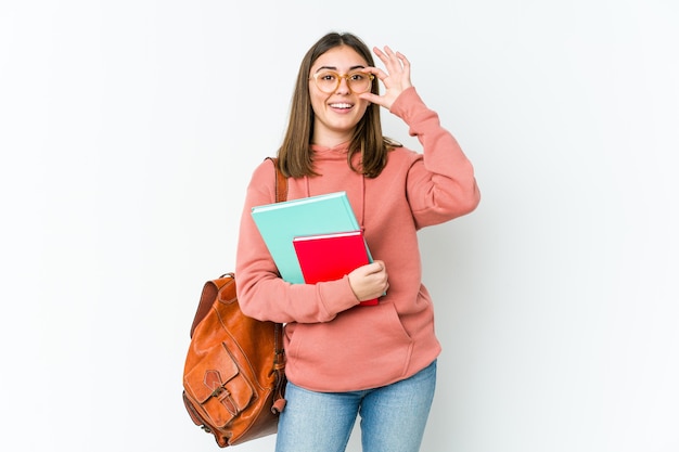 Mujer joven estudiante emocionada manteniendo el gesto ok en el ojo