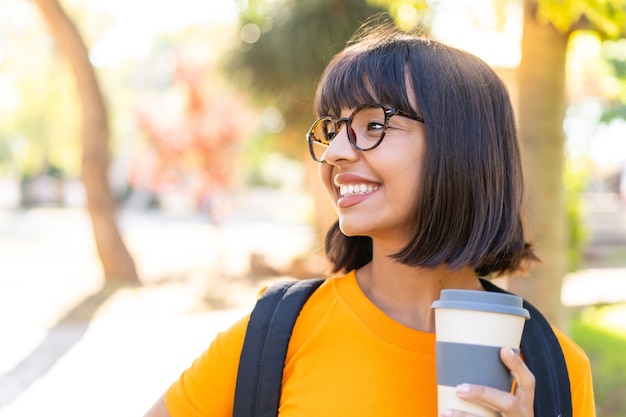 Mujer joven estudiante gana un parque con expresión feliz