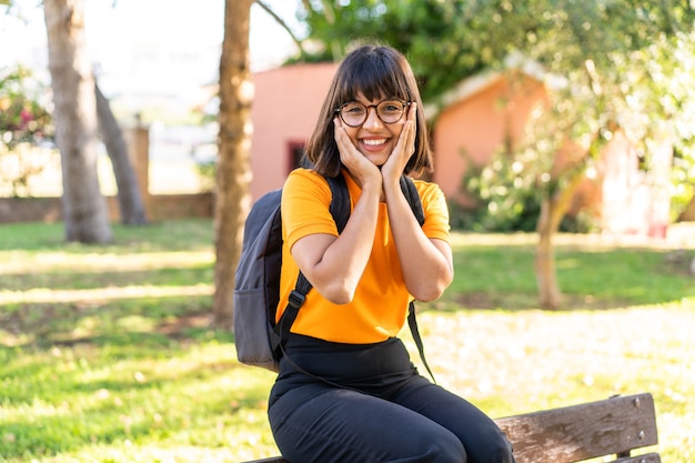 Mujer joven estudiante gana un parque con expresión feliz