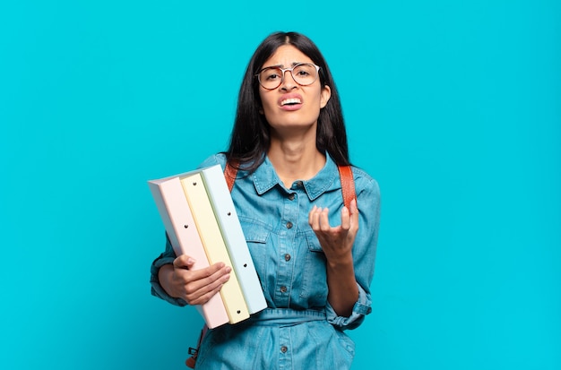 Mujer joven estudiante hispana que parece desesperada y frustrada, estresada, infeliz y molesta, gritando y gritando