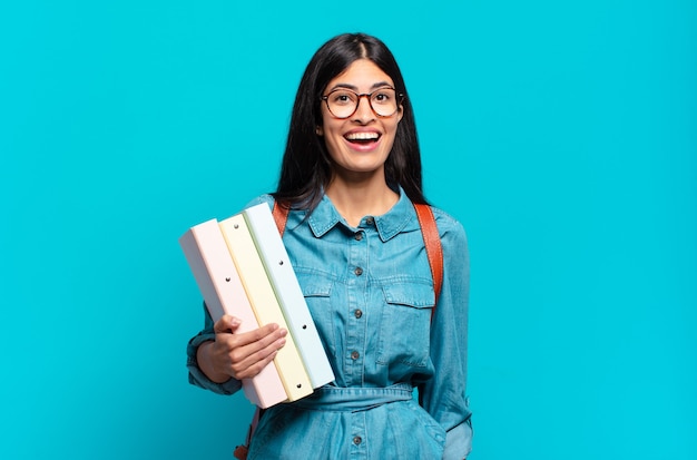 Mujer joven estudiante hispana que parece feliz y gratamente sorprendida, emocionada con una expresión fascinada y conmocionada