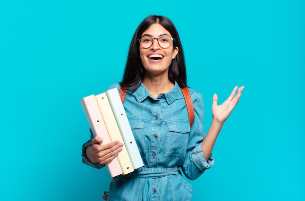 Mujer joven estudiante hispana que se siente feliz, sorprendida y alegre, sonriendo con actitud positiva, dándose cuenta de una solución o idea