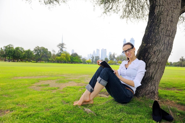 Mujer joven estudiante leyendo un libro y estudiando en el parque