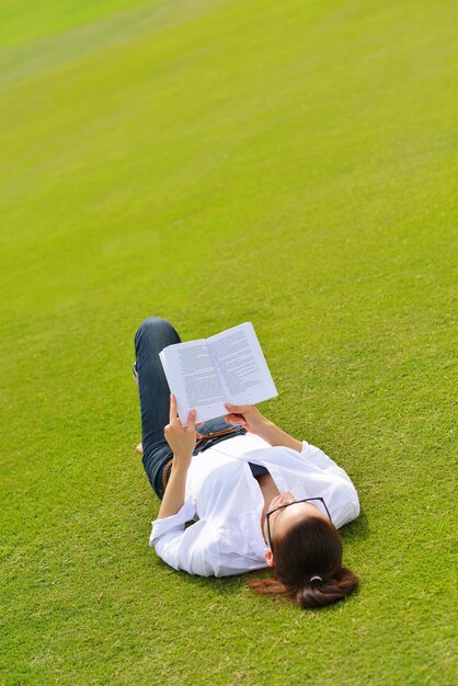 Mujer joven estudiante leyendo un libro y estudiando en el parque