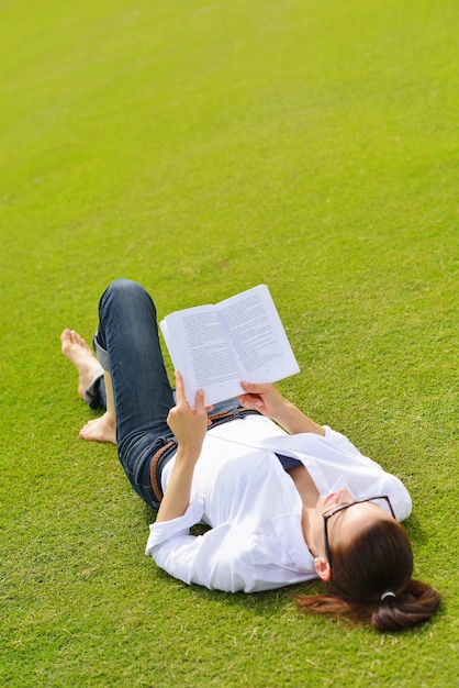 Mujer joven estudiante leyendo un libro y estudiando en el parque