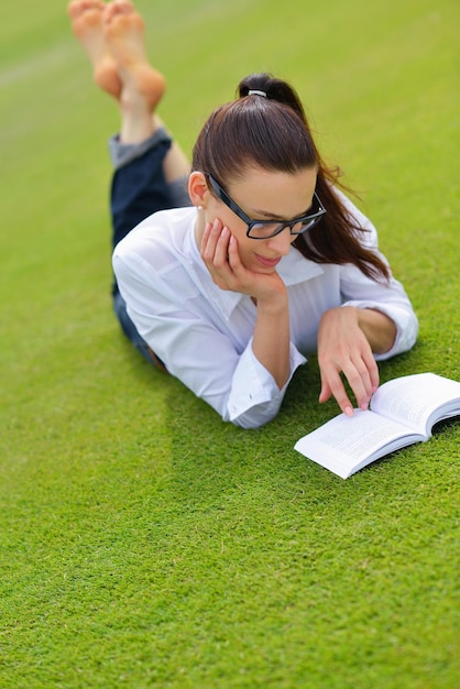 Mujer joven estudiante leyendo un libro y estudiando en el parque