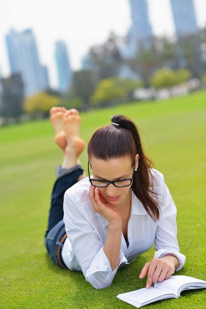 Mujer joven estudiante leyendo un libro y estudiando en el parque