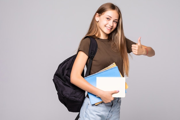 Mujer joven estudiante con mochila bolso de mano con el pulgar hacia arriba gesto, aislado sobre la pared blanca