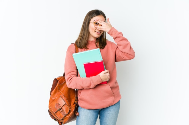 Mujer joven estudiante parpadeando a través de los dedos, avergonzado cubriendo la cara