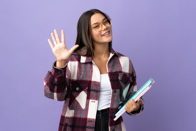 Mujer joven estudiante en púrpura contando cinco con los dedos