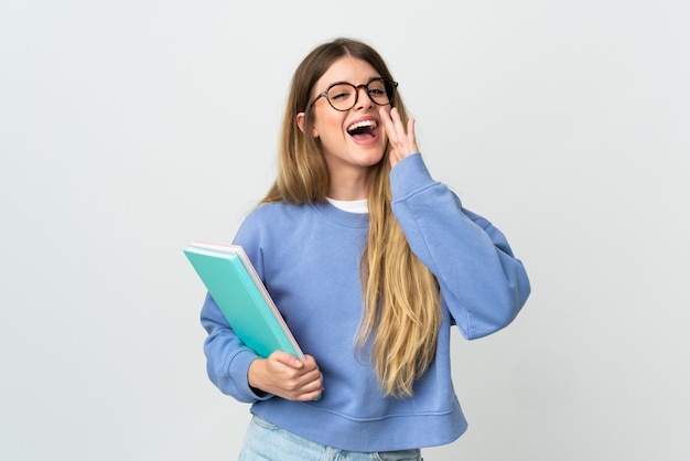 Mujer joven estudiante rubia en blanco gritando con la boca abierta