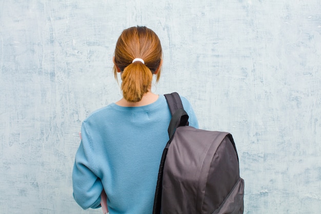 Mujer joven estudiante sentirse confundido o lleno o dudas y preguntas, preguntándose, con las manos en las caderas, vista trasera