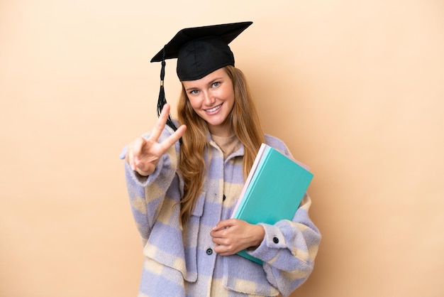 Mujer joven estudiante sobre fondo aislado sonriendo y mostrando el signo de la victoria