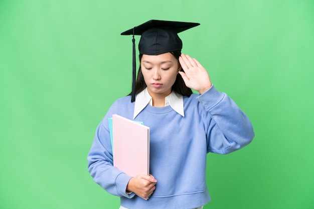 Mujer joven estudiante sobre fondo clave de croma aislado haciendo gesto de parada y decepcionada