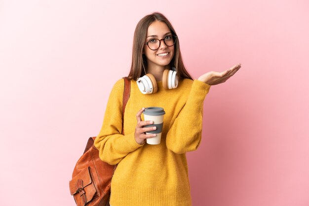 Mujer joven estudiante sobre fondo rosa aislado extendiendo las manos hacia el lado para invitar a venir