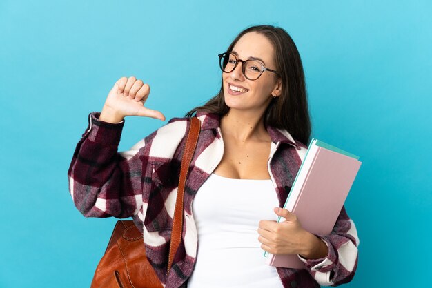 Mujer joven estudiante sobre pared aislada orgullosa y satisfecha de sí misma