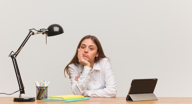 Mujer joven estudiante trabajando en su escritorio cansado y con mucho sueño