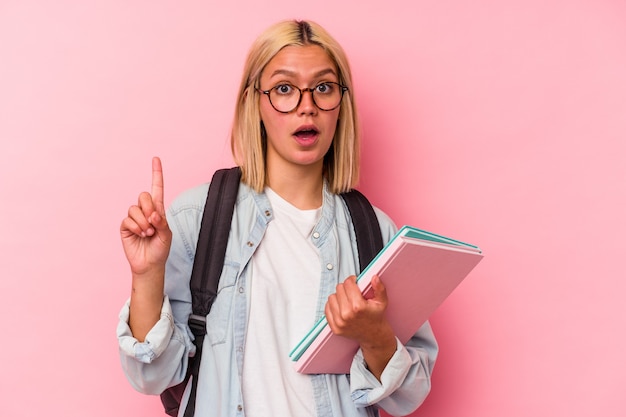 Mujer joven estudiante venezolana aislada en la pared rosa con una idea