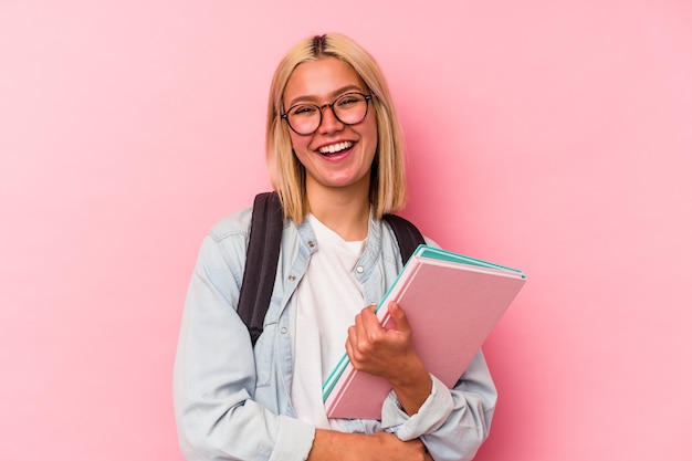 Mujer joven estudiante venezolana aislada sobre fondo rosa riendo y divirtiéndose.