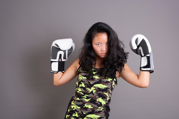 Foto mujer joven de etnia asiática con guantes de boxeo aislado sobre fondo