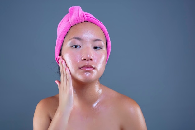 Mujer joven de etnia china cuidando su rostro con crema facial