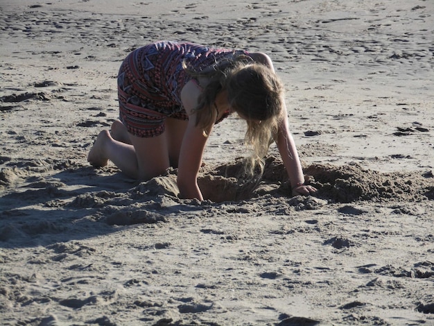 Foto mujer joven excavando arena en la playa