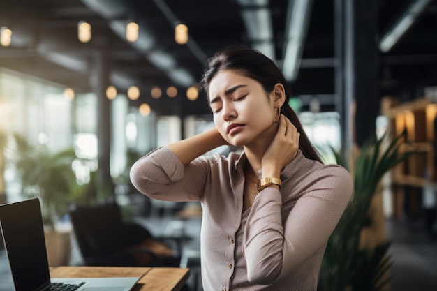 Mujer joven con exceso de trabajo que sufre de dolor de cuello en la oficina
