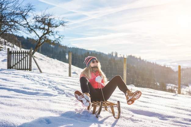 Mujer joven a exceso de velocidad con trineo vintage en alta montaña de nieve