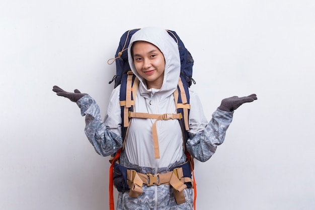 Mujer joven excursionista asiática con mochila dedo acusador en el espacio vacío sobre fondo blanco.