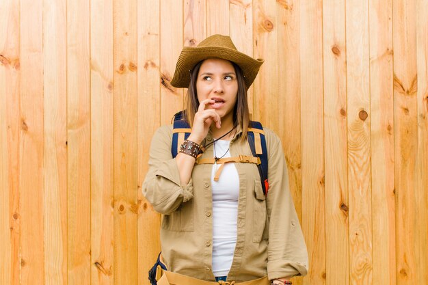 Mujer joven explorador latino contra la pared de madera