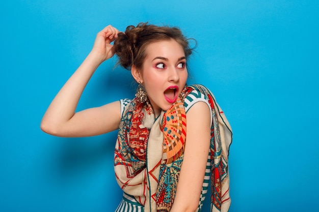 Mujer joven con expresión facial sorprendida sobre fondo azul.