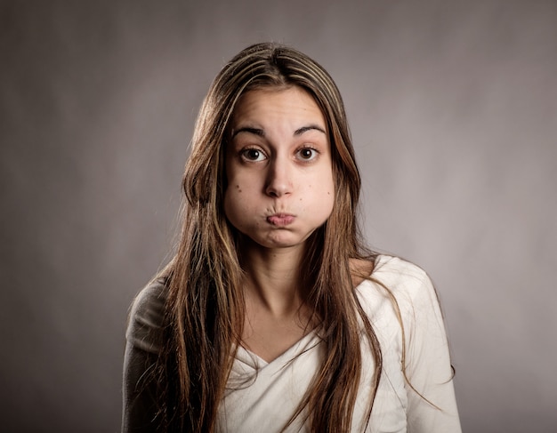 Mujer joven con expresión molesta en un gris