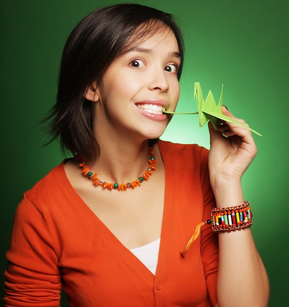 Mujer joven de expresión con pájaro de papel sobre verde