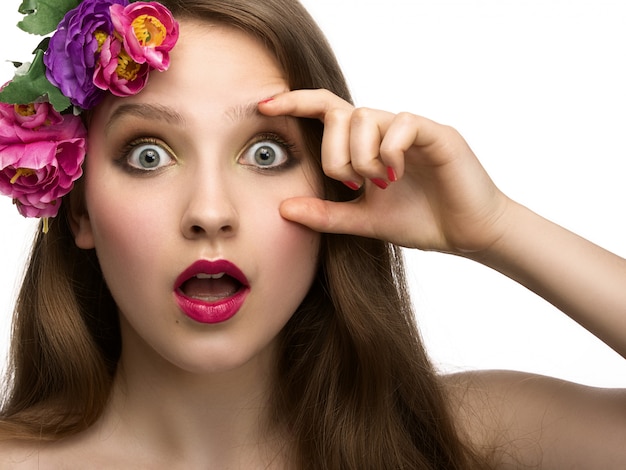 Mujer joven con expresión sorprendida con flores y labios rojos