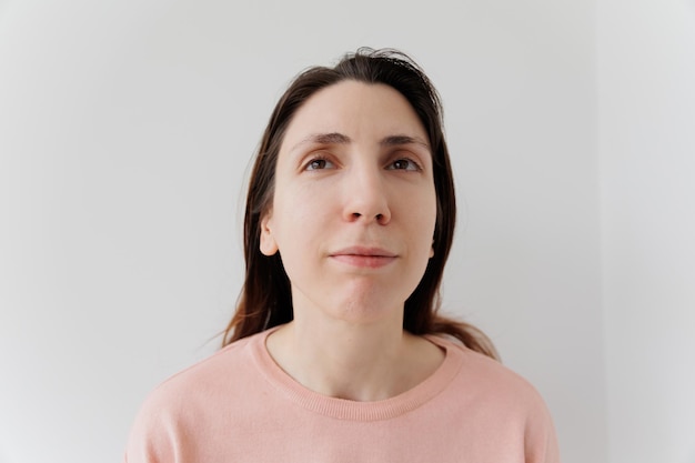 Mujer joven con extraña expresión facial feliz sobre fondo gris