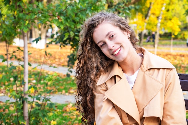 Mujer joven feliz en abrigo biege. Retrato de mujer de otoño. Copia espacio