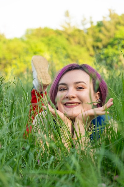 Mujer joven feliz acostada en la hierba en la naturaleza en verano