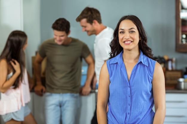 Mujer joven feliz con amigos en segundo plano en casa