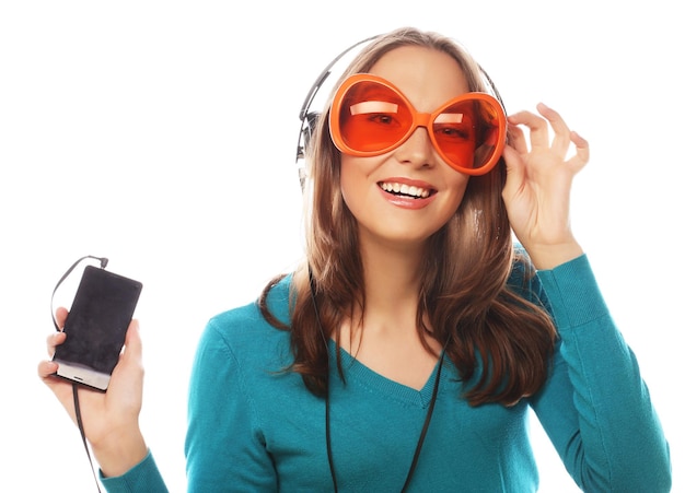 Foto mujer joven feliz con auriculares escuchando música sobre fondo blanco.