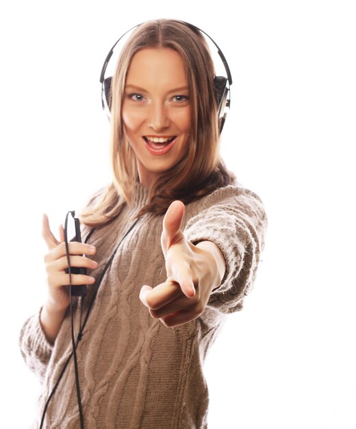 Mujer joven feliz con auriculares escuchando música sobre fondo blanco.