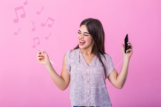 Mujer joven feliz con auriculares escuchando música desde el teléfono inteligente