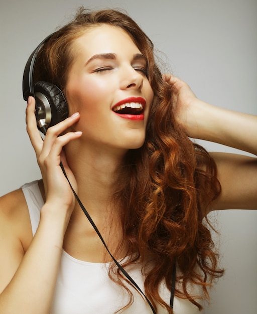 Mujer joven feliz con auriculares escuchando música