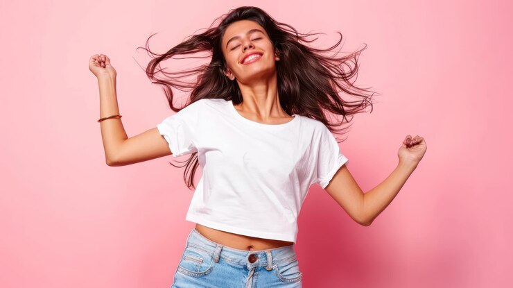 Mujer joven feliz bailando sobre un fondo rosa alegría y concepto despreocupado con espacio de copia