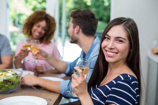 Mujer joven feliz bebiendo vino con amigos