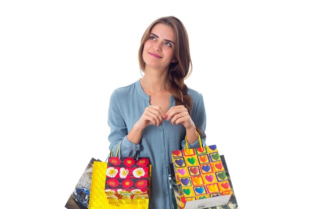 Foto mujer joven feliz en blusa azul con bolsas de compras multicolores en sus manos en el estudio